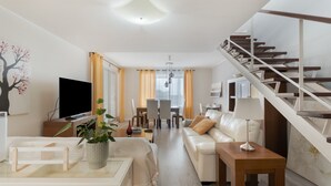 A modern living room with a sofa, TV, and a staircase. - Independent Villa in Exclusive Chayofa, Near Los Cristianos and Siam Park (Chayofa)