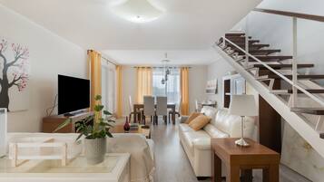 Een moderne woonkamer met een bank, televisie en een trap.