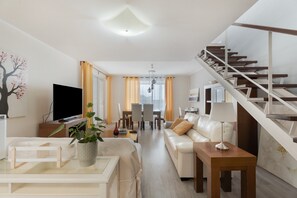 A modern living room with a sofa, TV, and a staircase. - Independent Villa in Exclusive Chayofa, Near Los Cristianos and Siam Park (Chayofa)
