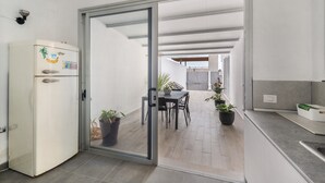 A modern kitchen with a refrigerator, a dining area with chairs and a table, and a sliding glass door leading to an outdoor space. - Independent Villa in Exclusive Chayofa, Near Los Cristianos and Siam Park (Chayofa)