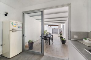A modern kitchen with a refrigerator, a dining area with chairs and a table, and a sliding glass door leading to an outdoor space. - Independent Villa in Exclusive Chayofa, Near Los Cristianos and Siam Park (Chayofa)