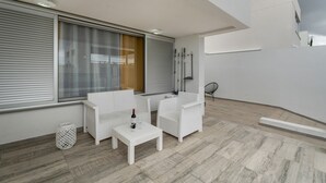 A balcony with white furniture, a table with a bottle and glass, and a view of the city. - Independent Villa in Exclusive Chayofa, Near Los Cristianos and Siam Park (Chayofa)