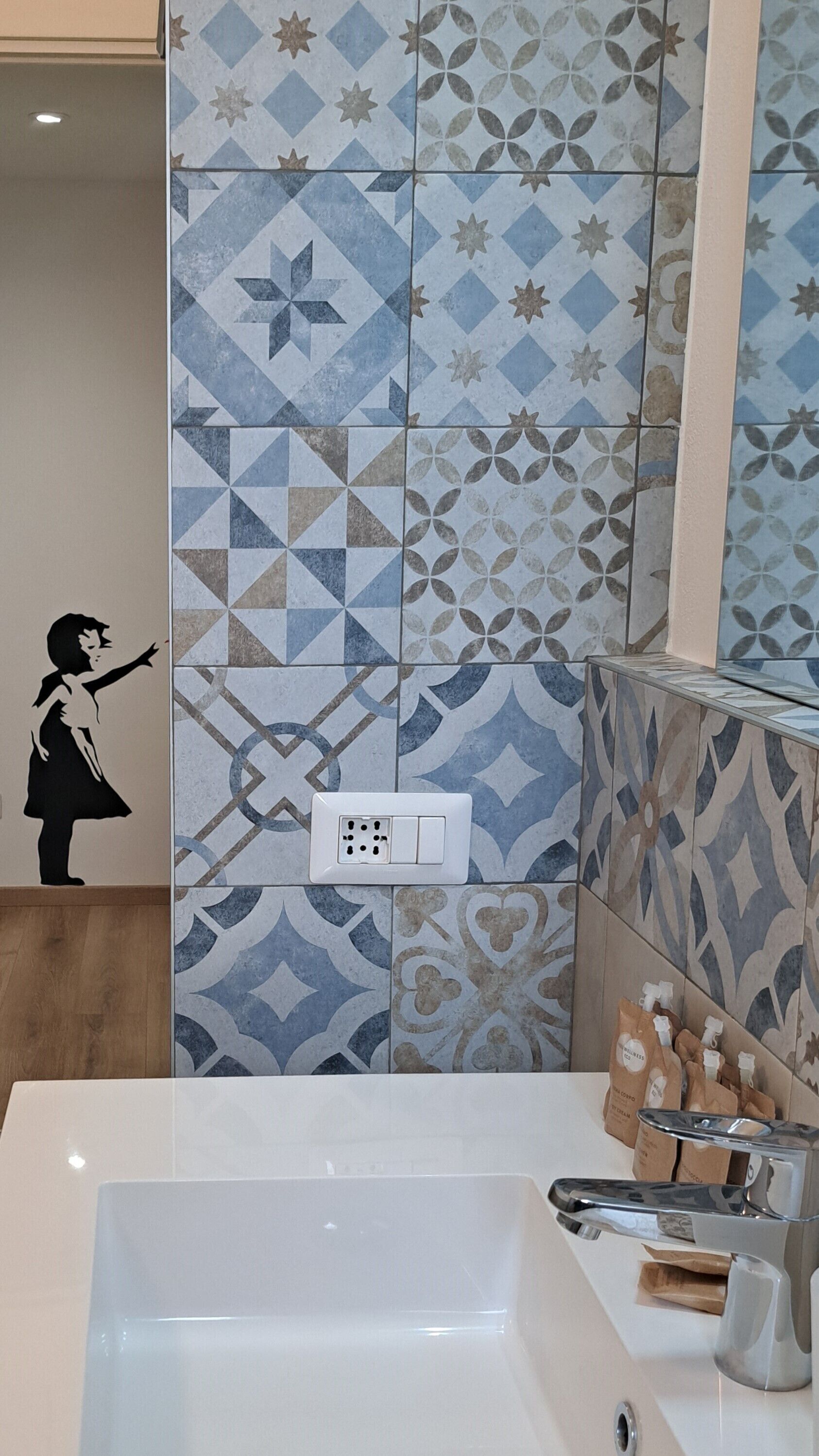 Un baño con bañera, espejo y azulejos estampados.