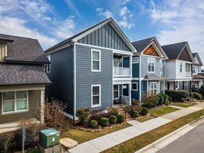 A two-story residential building with a balcony, a front yard with landscaping, and a clear sky. - Walk to Southside Dining, Stylish 3BR w Easy Parking (Chattanooga)