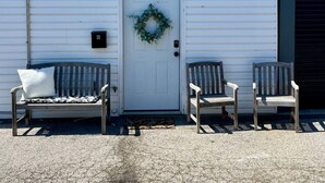 A white building with a front door, two wooden benches, and a wreath on the door. - Newly Furnished St. Charles Getaway- B (Saint Charles)