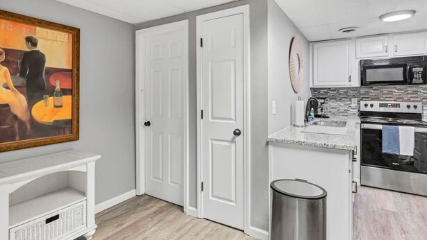 A kitchen with white cabinets, a microwave, an oven, and a trash can. - Newly Furnished St. Charles Getaway- B (Saint Charles)
