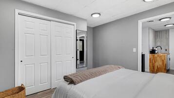 Une chambre avec un lit, une armoire, un miroir et une petite kitchenette.