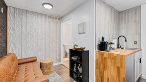 A compact living space with a kitchenette, a sofa, and a woven basket.