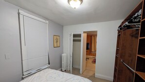 Une chambre à coucher comprenant un lit, un radiateur, une armoire et une porte donnant sur une autre pièce.