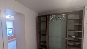 Un dressing accessible sans porte, doté d’étagères ouvertes et d’un grand miroir sur toute la hauteur.