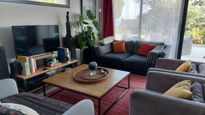 Un salon moderne avec un téléviseur à écran plat, des livres, un globe terrestre et un canapé agrémenté de coussins à rayures.