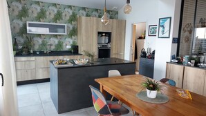 Une cuisine moderne dotée d’un îlot central, de meubles de rangement en bois et d’un coin repas avec une table et des chaises en bois.