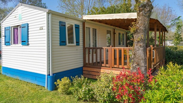 A mobile home with a porch, a covered area, and a number '09' on the side. - Mobile Home Near Royan with Shared Pool, Private Terrace, and Wi-Fi (Meschers-sur-Gironde)
