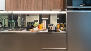 Uma cozinha moderna com eletrodomésticos de aço inoxidável, armários de madeira e bancada com diversos objetos.