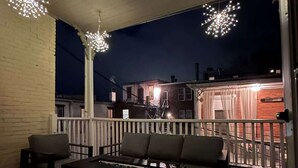 Un espacio al aire libre con un patio, barandilla blanca, un sofá y una mesa.