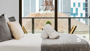 Une chambre d’hôtel avec un lit, des oreillers et une vue sur un immeuble doté d’une tour.
