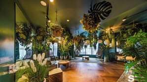 Une pièce spacieuse dotée d’un plancher en bois, de plusieurs coins salon et d’une abondance de plantes d’intérieur.