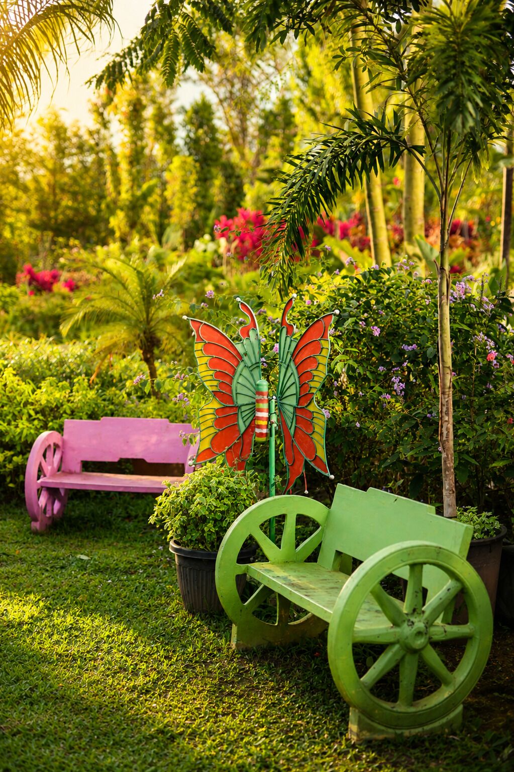 A garden with a green bench, a pink bench, and a decorative butterfly sculpture.