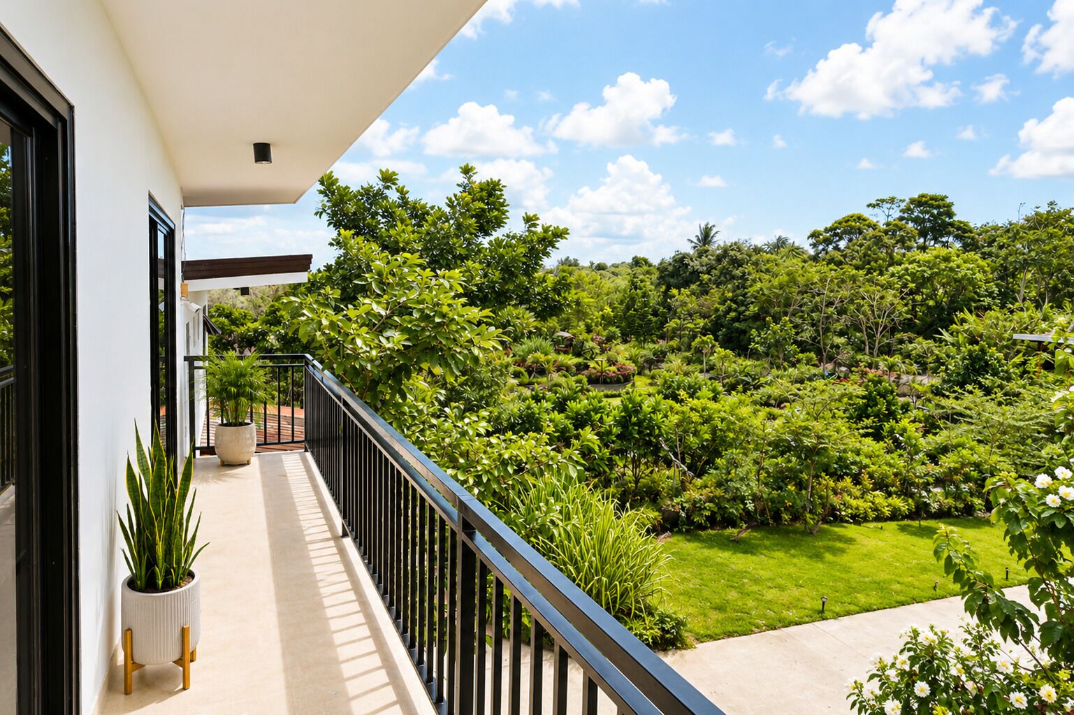 A balcony with a view of a lush garden and a clear sky.