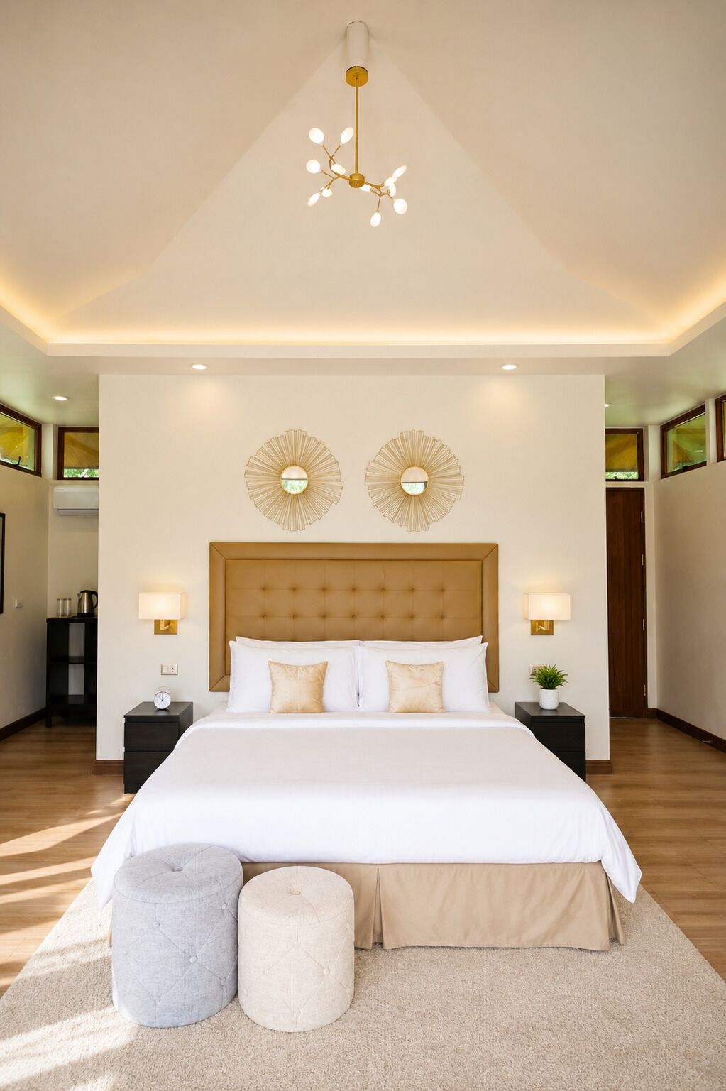 Un dormitorio moderno con una cama grande, dos apliques de pared, un cabecero capitonado y una lámpara colgante.