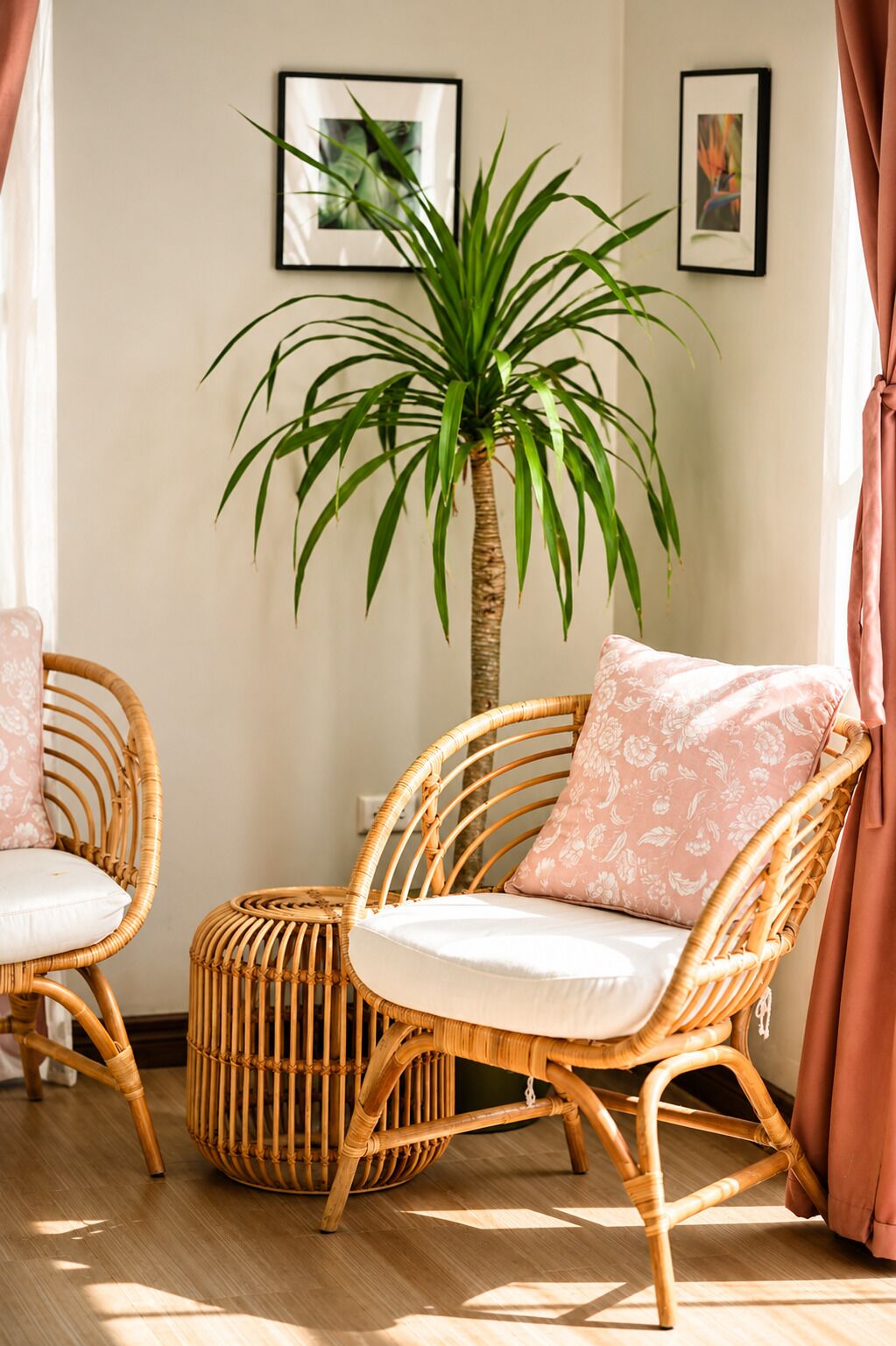 Een kamer met rieten stoelen, een rond poef en een hoge potplant.