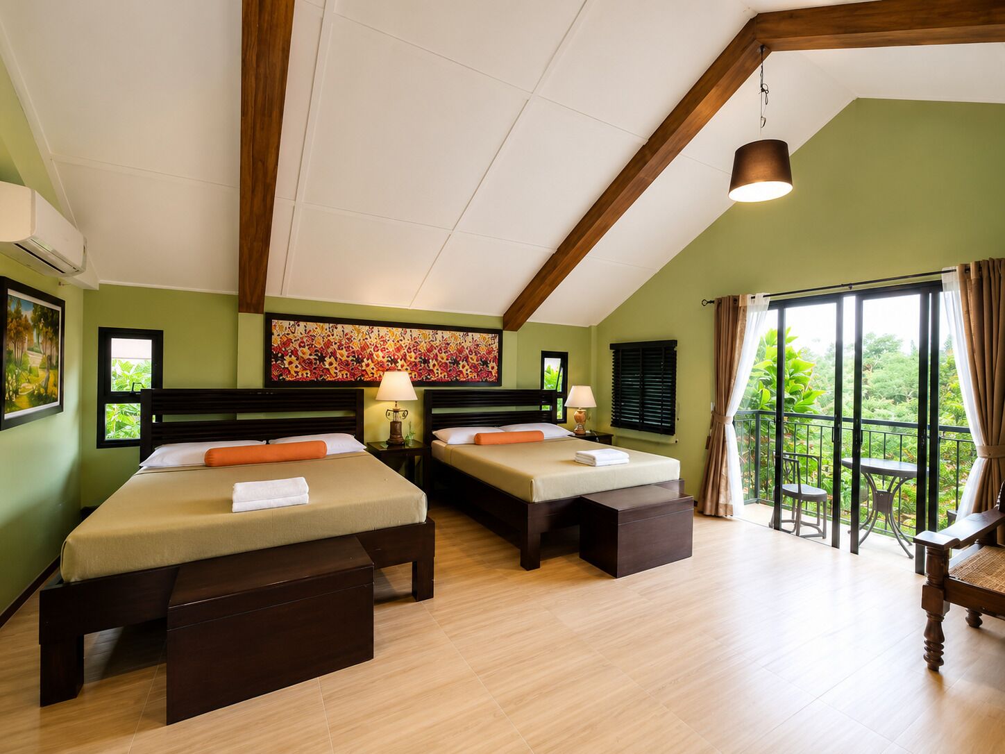 Hotelkamer met twee bedden, een balkon met een tafel en stoelen en een groot raam met gordijnen.