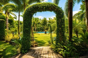 Un jardin luxuriant avec un chemin de briques menant à une piscine.