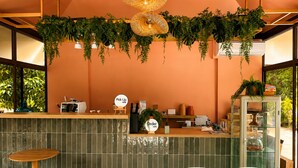 Een restaurant met een toonbank, zitgedeelte en hangende planten.