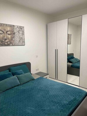 A bedroom with a bed, a wardrobe, and a wall-mounted artwork. - Zen Apt in the Heart of Malta (Ta` Xbiex)