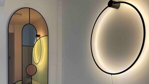 A modern living room with a sofa, a round mirror, and a wall-mounted light fixture. - Zen Apt in the Heart of Malta (Ta` Xbiex)