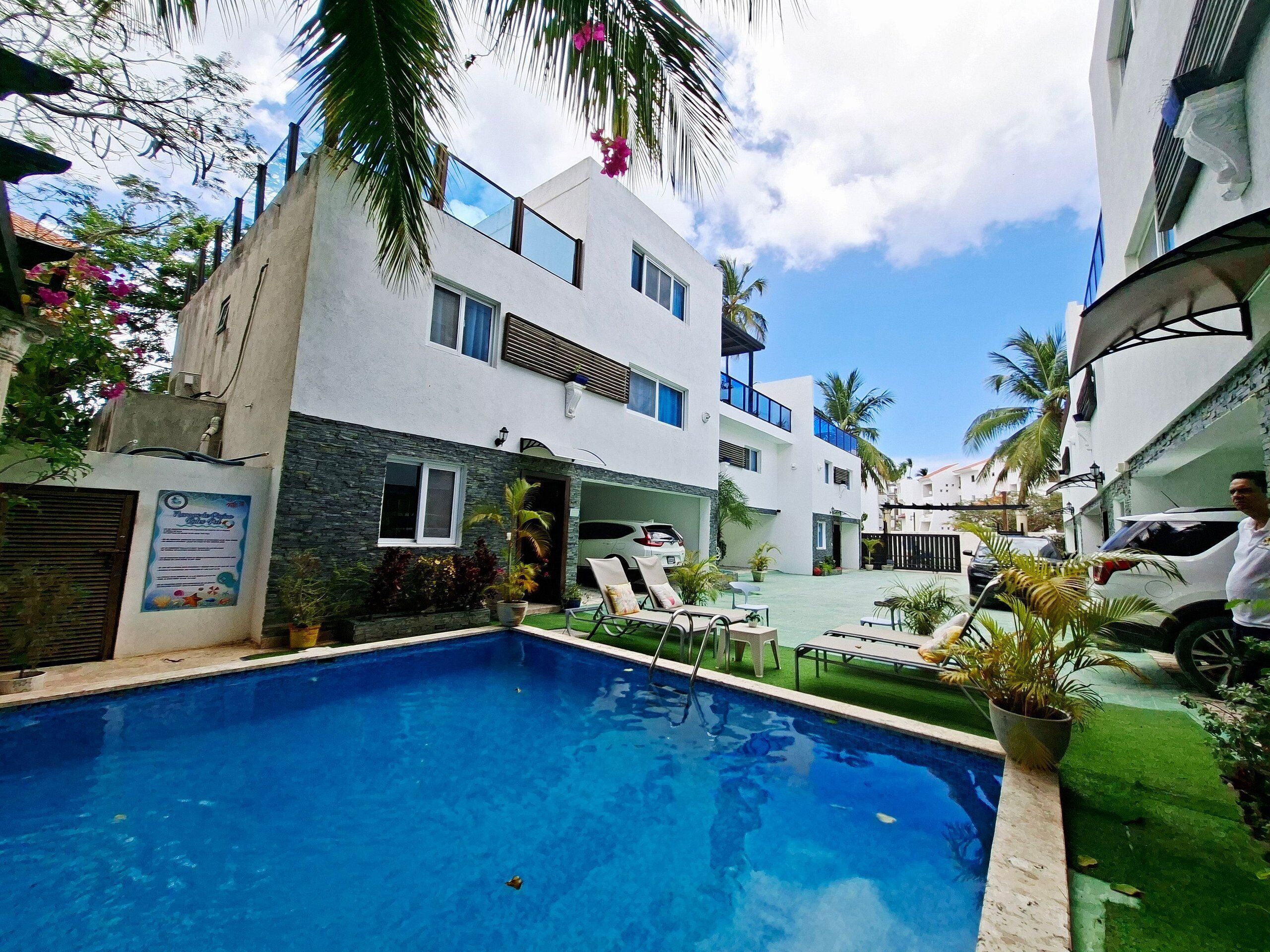 Un bâtiment moderne doté d’une piscine, de nombreux balcons et d’un jardin bien entretenu.