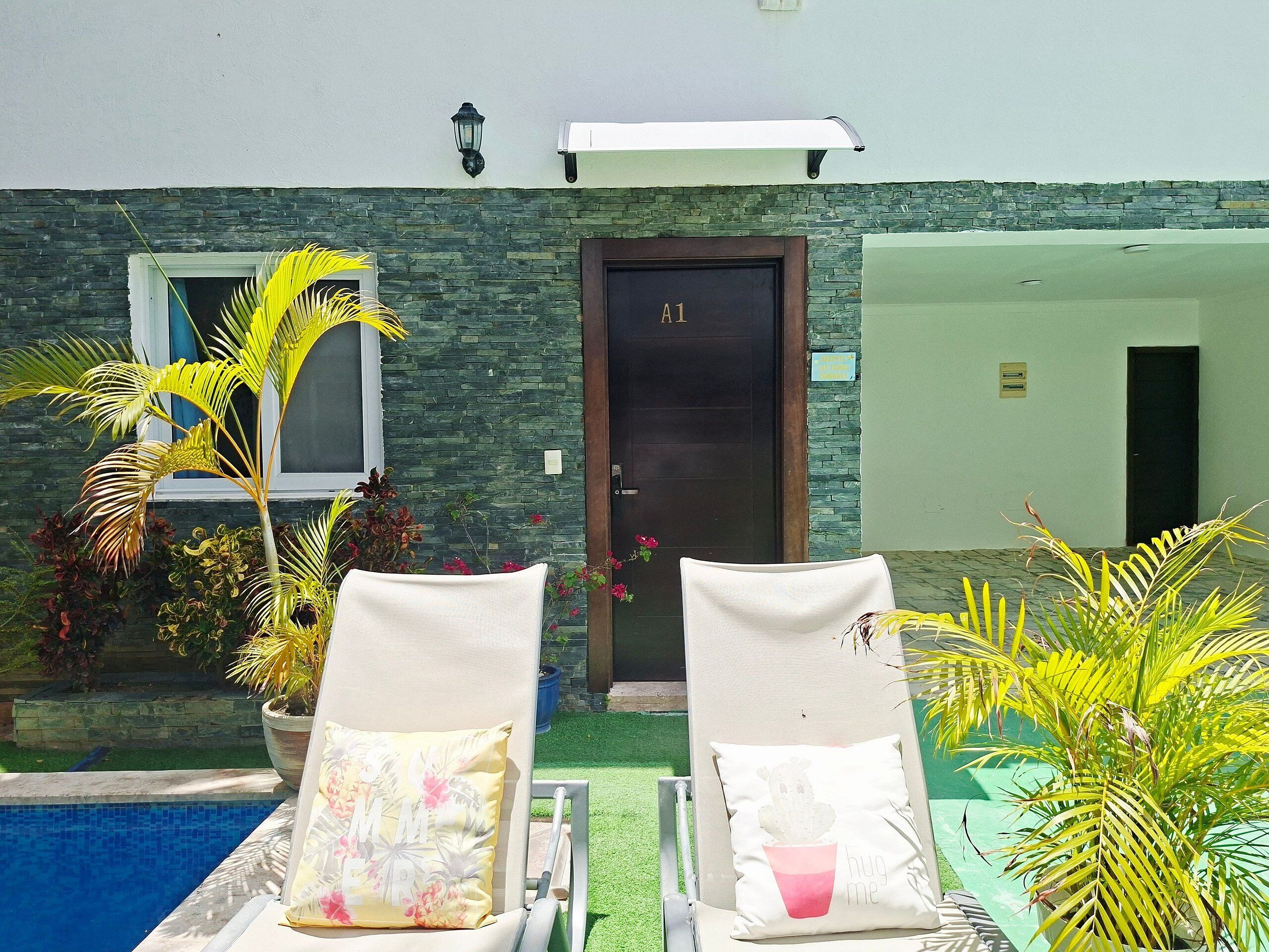 Two lounge chairs with cushions, a pool, a stone wall, and a door labeled 'A1'.