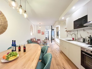 A modern kitchen with a marble countertop, a dining area with a wooden table and chairs, and a living room with a sofa and a TV. - 224 - Central Large Parisian Flat (París)