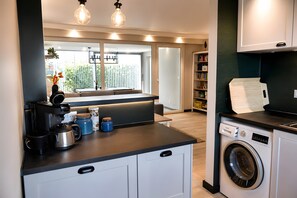 A compact kitchen with a coffee maker, toaster, and a washing machine. - Buddelhuus – Your Favorite Holiday Home by the North Sea (Norden)