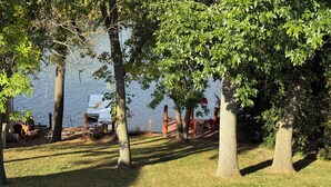 A lakeside area with trees, a dock, and outdoor seating.