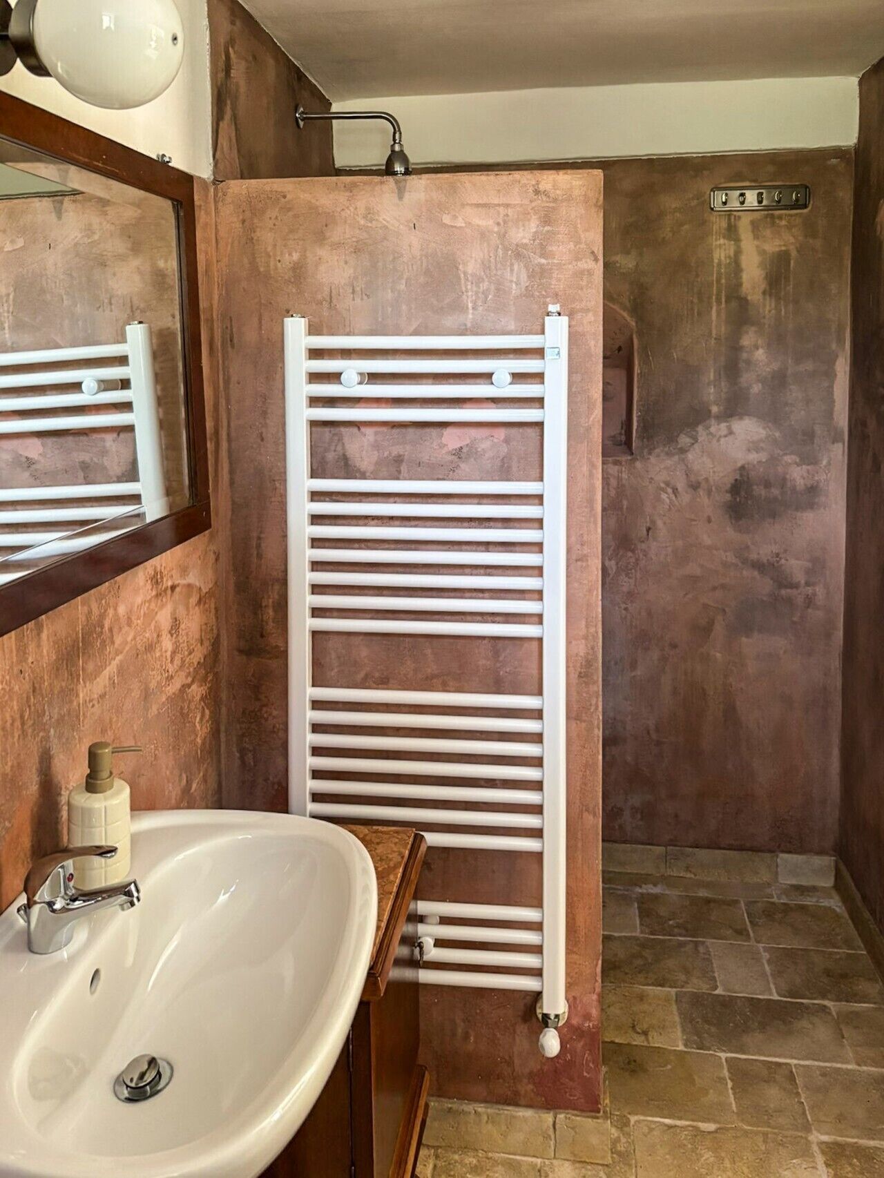 A bathroom with a white sink, a mirror, a towel rack, and a shower area.