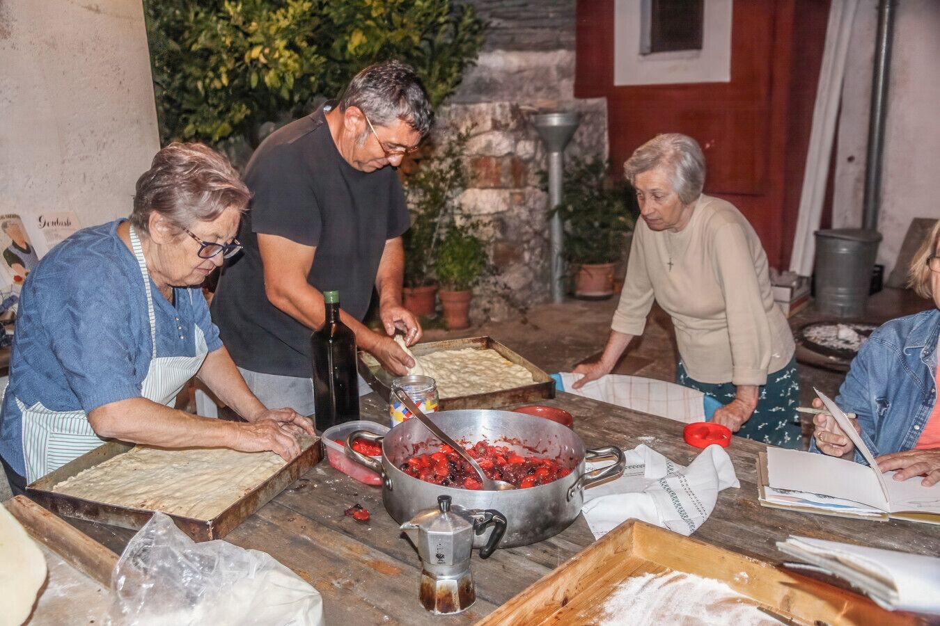 A group of people preparing food outdoors with a table, a large pot, and various kitchen utensils.