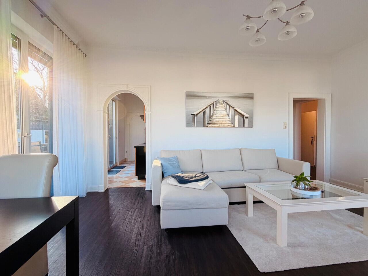 Un salon moderne comprenant un canapé, un pouf, une table basse et un tableau représentant un pont.