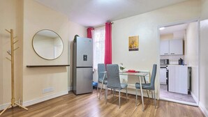 Un espacio habitable compacto con comedor, cocina y perchero.