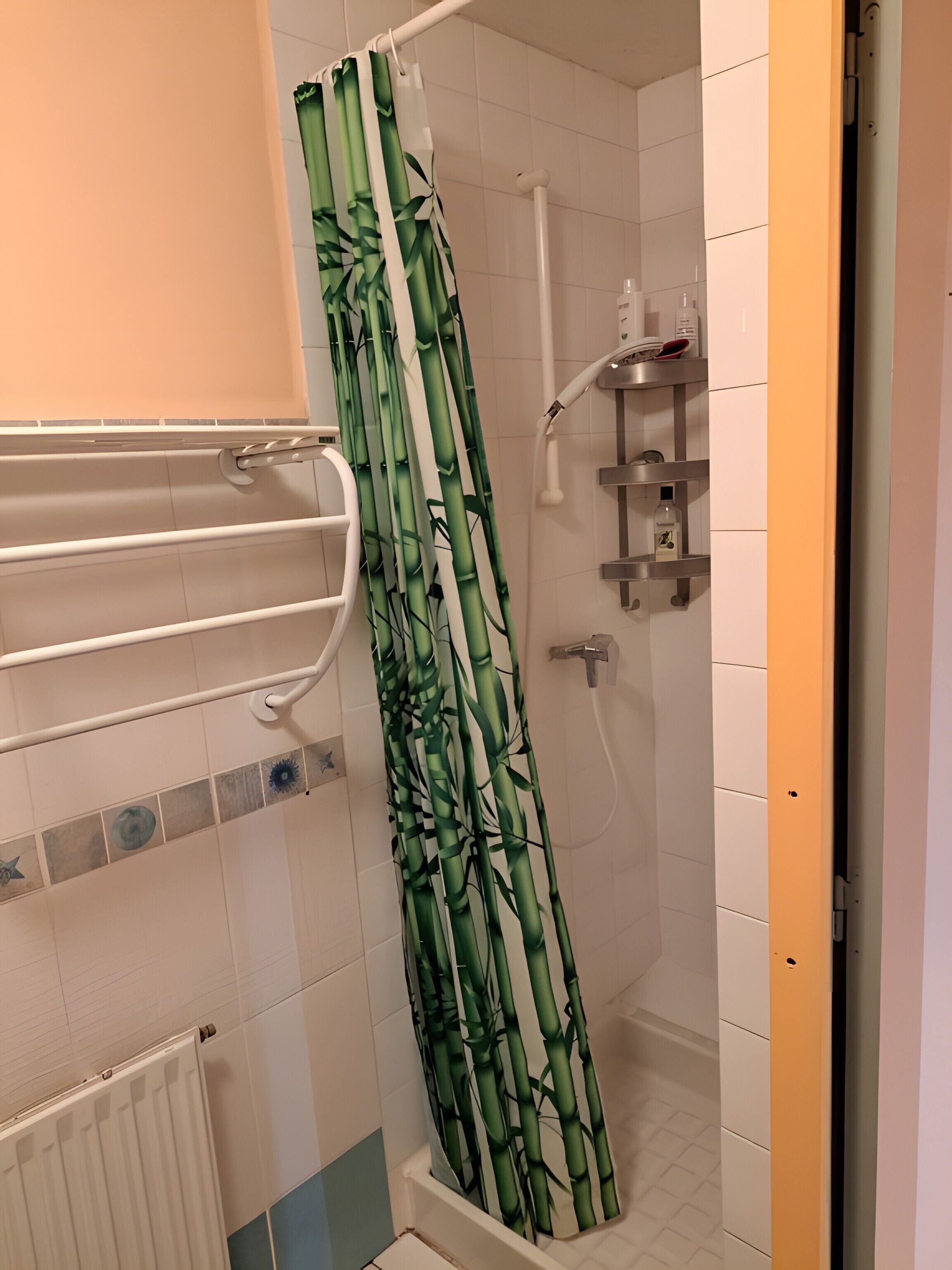 A shower with a bamboo shower curtain, a white towel rack, and a small shelf with toiletries.