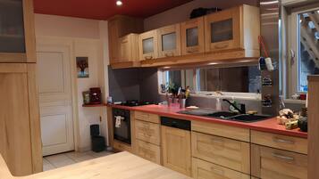 A kitchen with wooden cabinets, a red countertop, a dishwasher, and a sink.