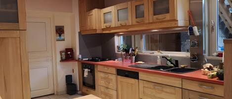 Una cocina con armarios de madera, encimera roja, lavavajillas y un lavabo.