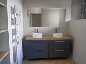 Ein Badezimmer mit zwei Waschbecken, einem Spiegel und einer Dusche.