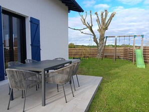 Eine Terrasse mit Tisch und Stühlen, einem Baum und einem Holzzaun.