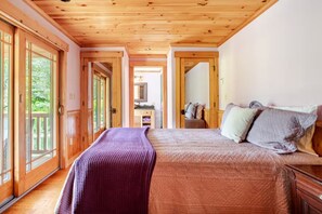 A bedroom with a wooden ceiling, a bed with pillows, a nightstand, and a view through a glass door. - East Branch Nature House - Spring Water Retreat (East Branch)