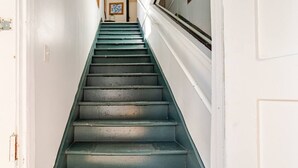 A staircase with a white door at the top and a window on the right side.