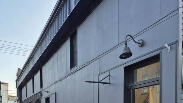 A modern building with a flat facade, large windows, and a visible entrance.