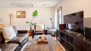 A living room with a sofa, a coffee table, a TV, and a plant.