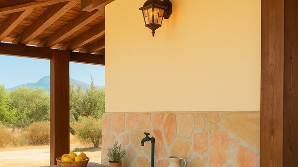 A stone bench with a woven rug, a potted plant, a basket of lemons, and a wall-mounted light fixture.