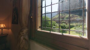 A room with a window, a lamp, and a painting on the wall.